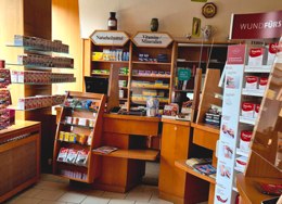 Innenansicht einer Apotheke mit Beratungsplatz, Regalen für Naturheilmittel und Vitamine sowie Freiwahlartikeln im Verkaufsraum.