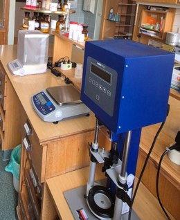 Laborarbeitsplatz in der Apotheke mit Waage, Prüfgerät und Gefäßen zur Herstellung und Qualitätskontrolle von Rezepturen.